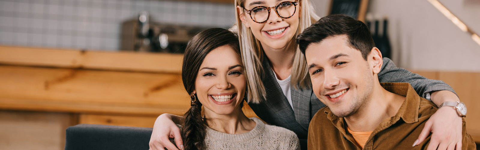 Cheerful woman in glasses hugging smiling friends